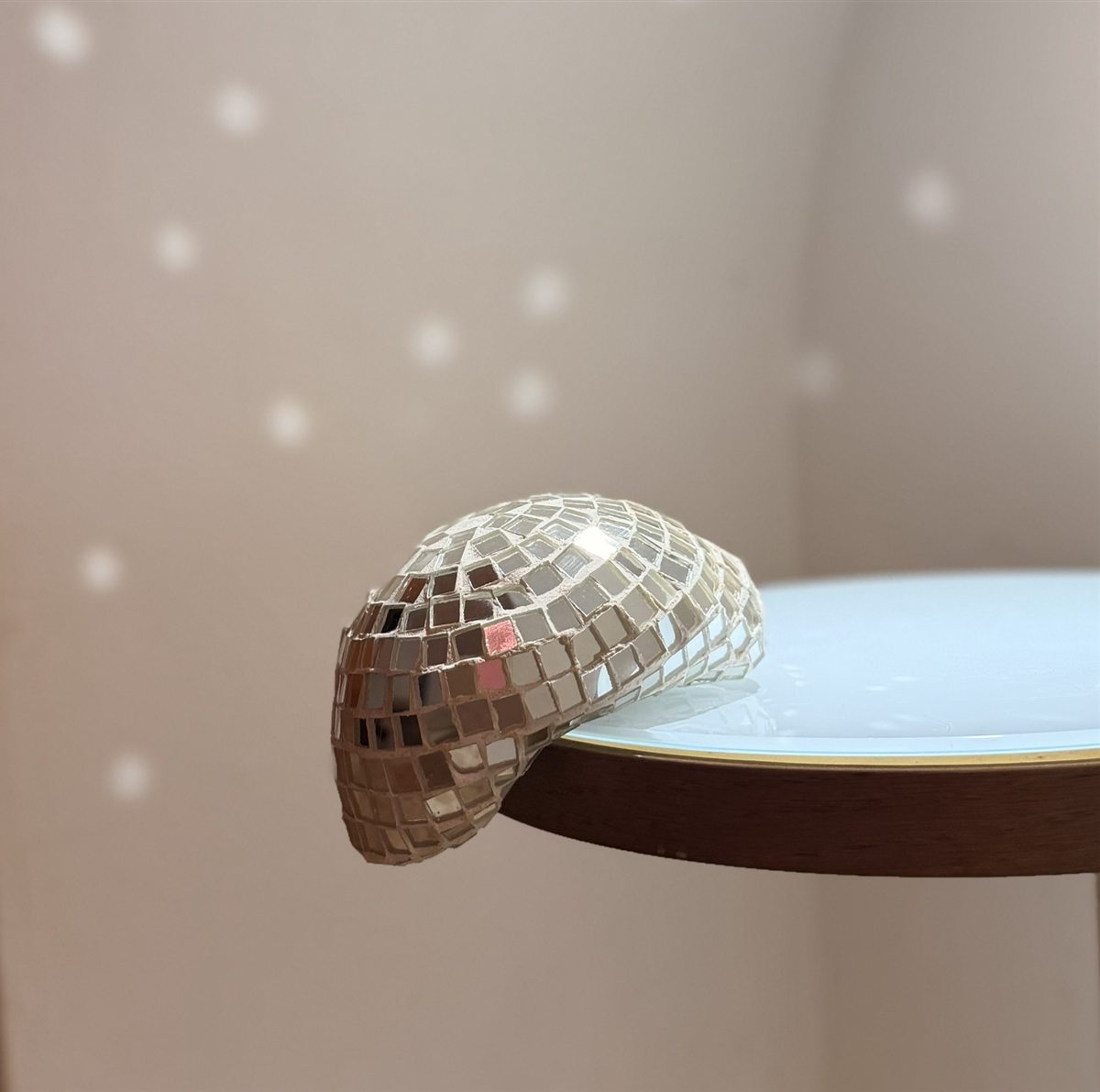 Fiesta Inesperada: a mirrored mosaic sphere spilling over the edge of a table